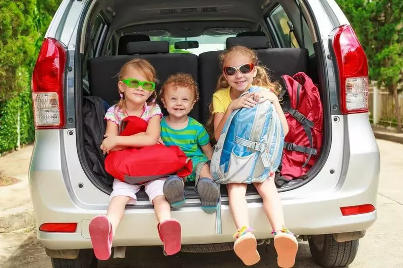 Three happy kids in the back of a car