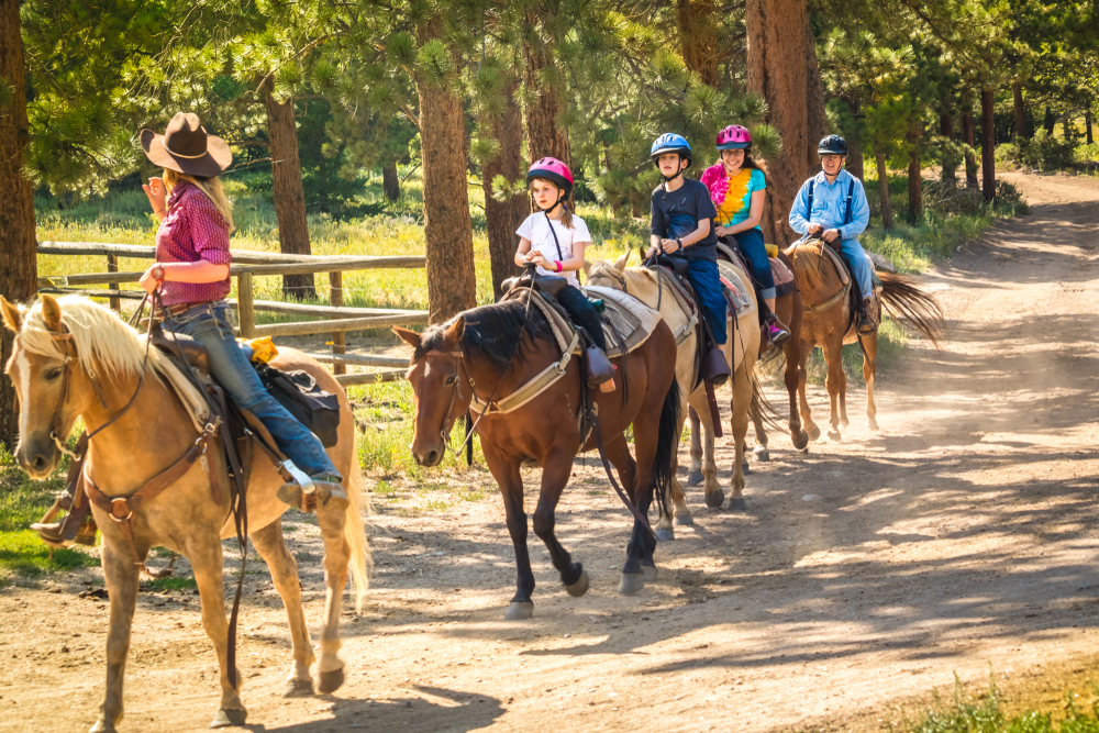 family horseback riding through woods